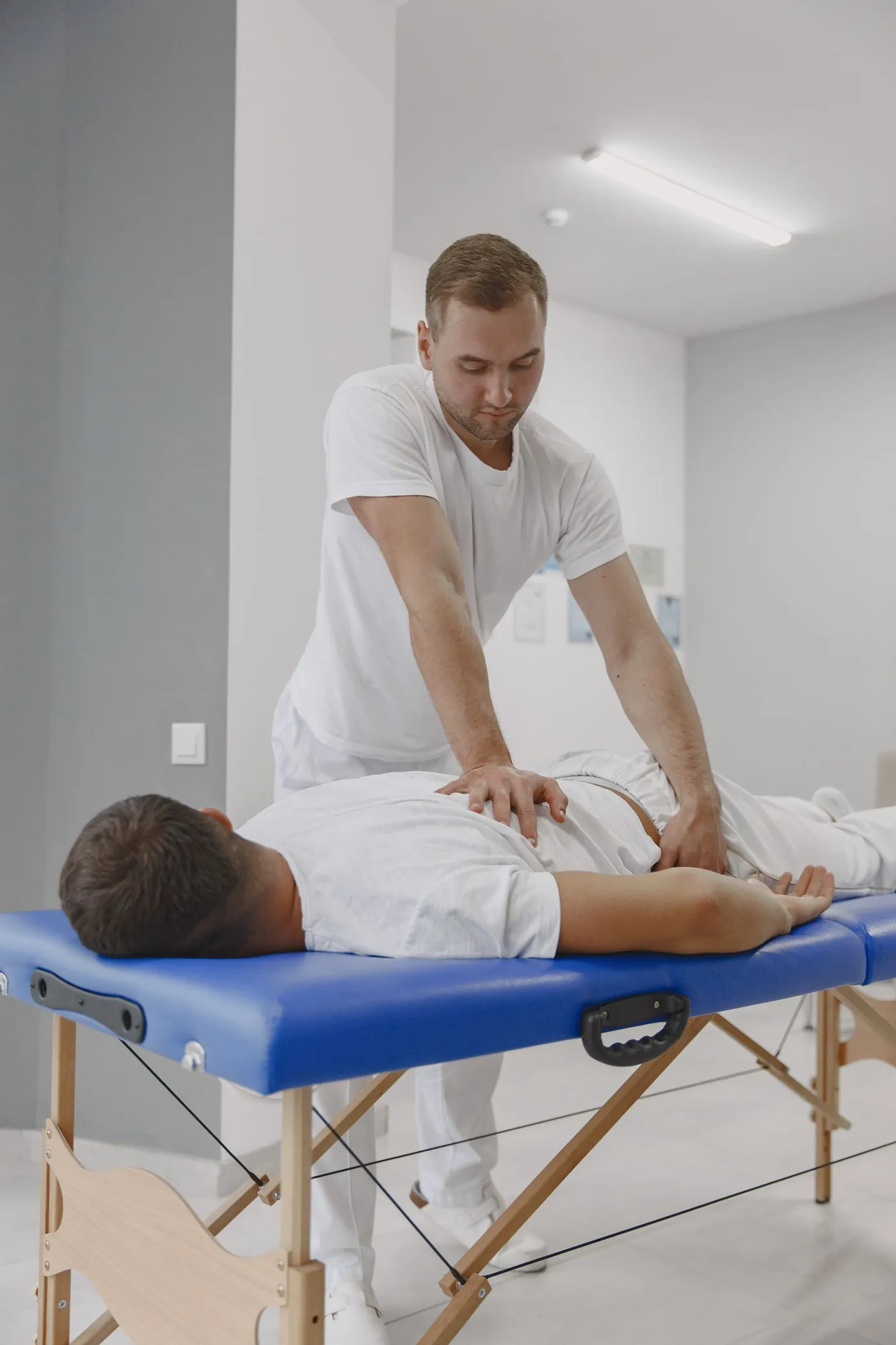 A clinician examining a patient's back on an examination table
