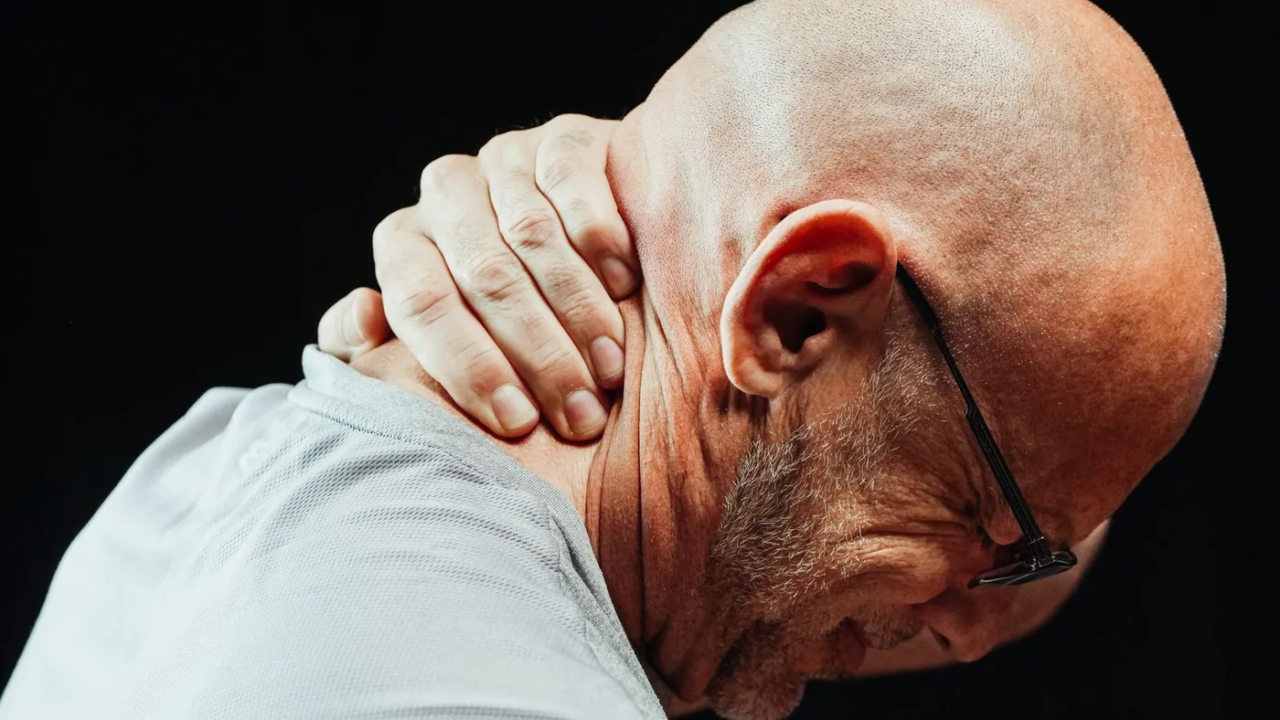 An older man holding his neck in pain