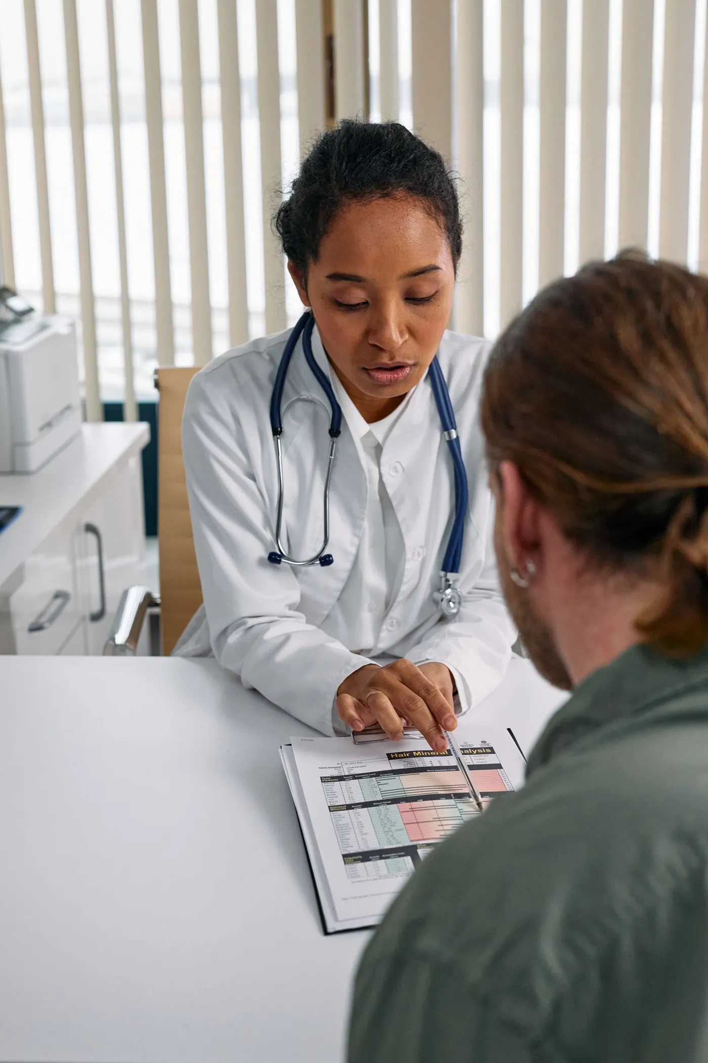 A doctor discussing a report with a patient at the desk