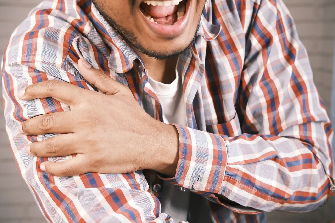 A man holding his painful arm and shoulder